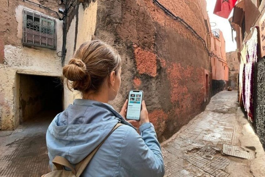 A person taking a photo with a smartphone in a narrow alleyway with old buildings. 1