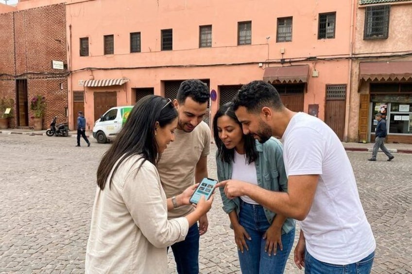 A group of people standing on a cobblestone street, looking at a smartphone. 4