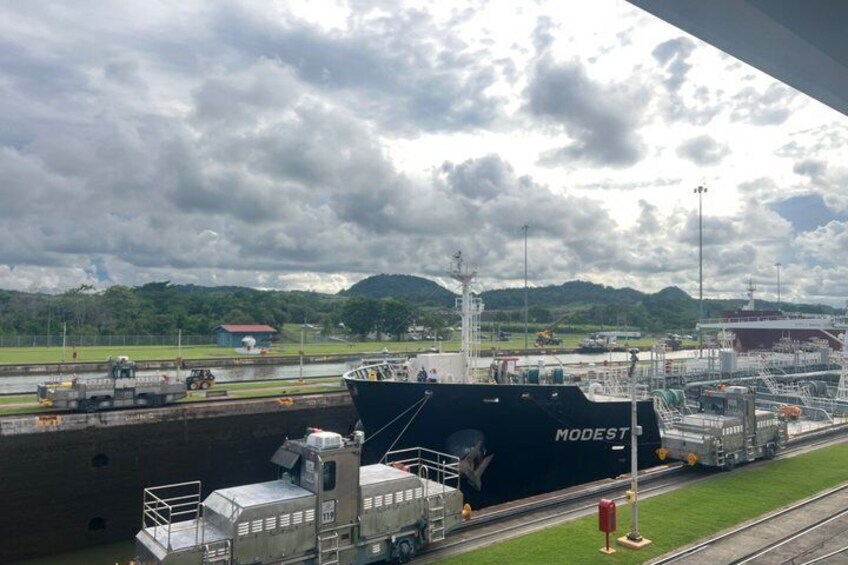 A large ship docked at a port with a lock system, surrounded by industrial structures and a cloudy sky. 2