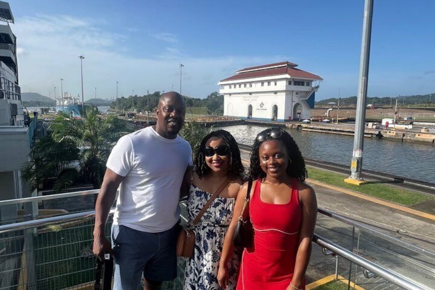 Three people standing on a bridge with a waterway and a building in the background. 3
