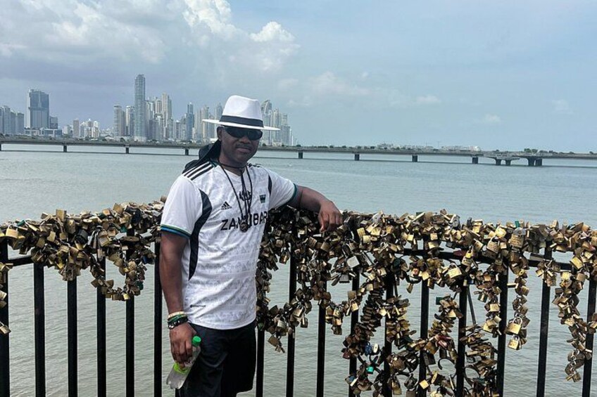 A man standing by a river with a city skyline in the background. 5