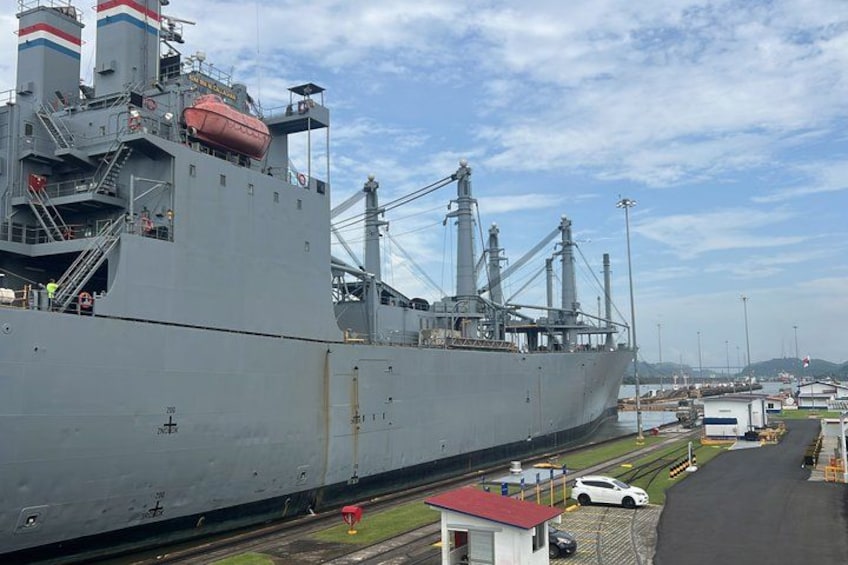 A large cargo ship docked at a port with cranes and a small building nearby. 5