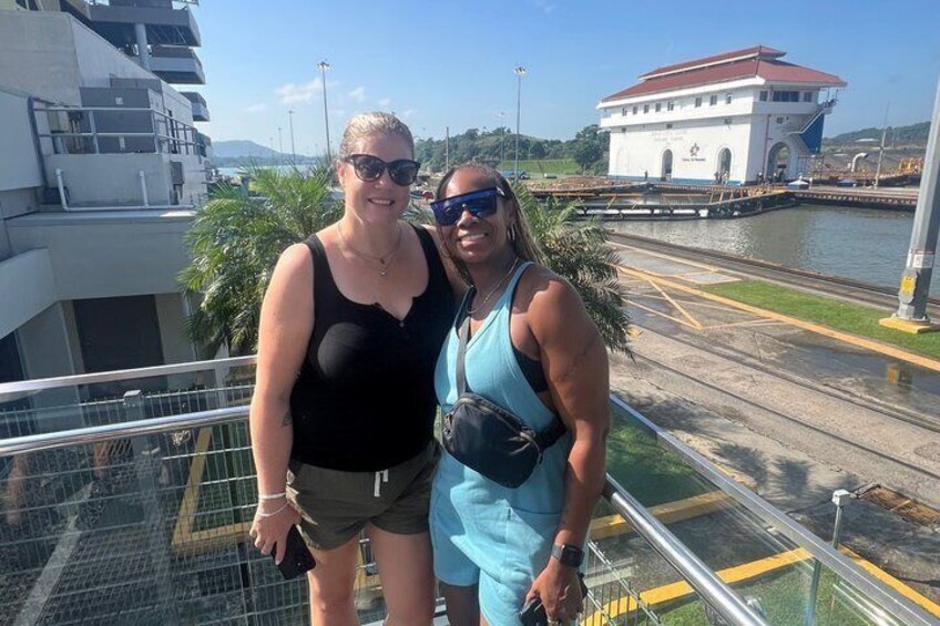 Two people standing on a balcony with a waterway and a building in the background. 5
