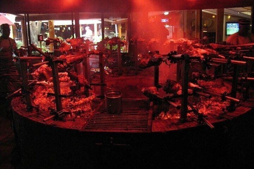 A dimly lit indoor space with a central grill area, surrounded by seating and a counter. 4