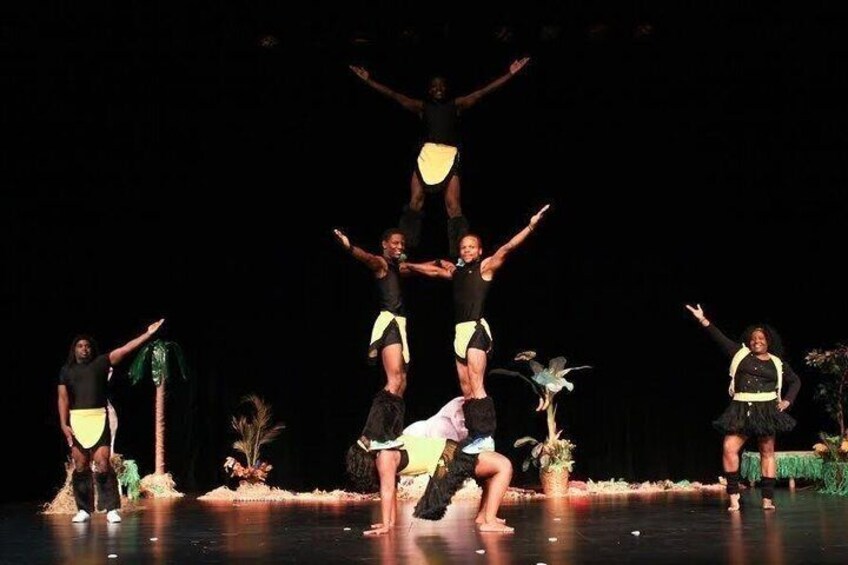 A group of dancers performing on a stage with a dark background. 5