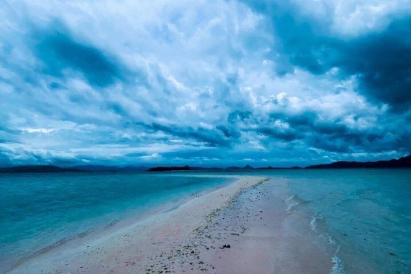 A beach with a clear path leading to the water, surrounded by a cloudy sky. 2