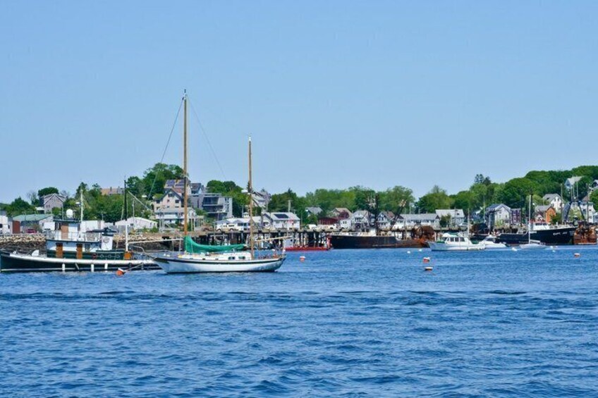 Un puerto con barcos, un faro y un pueblo costero. 4