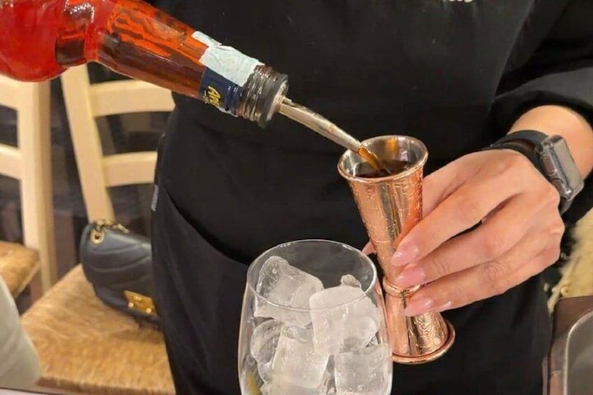 En person häller en röd vätska i en kopp av koppar. 3