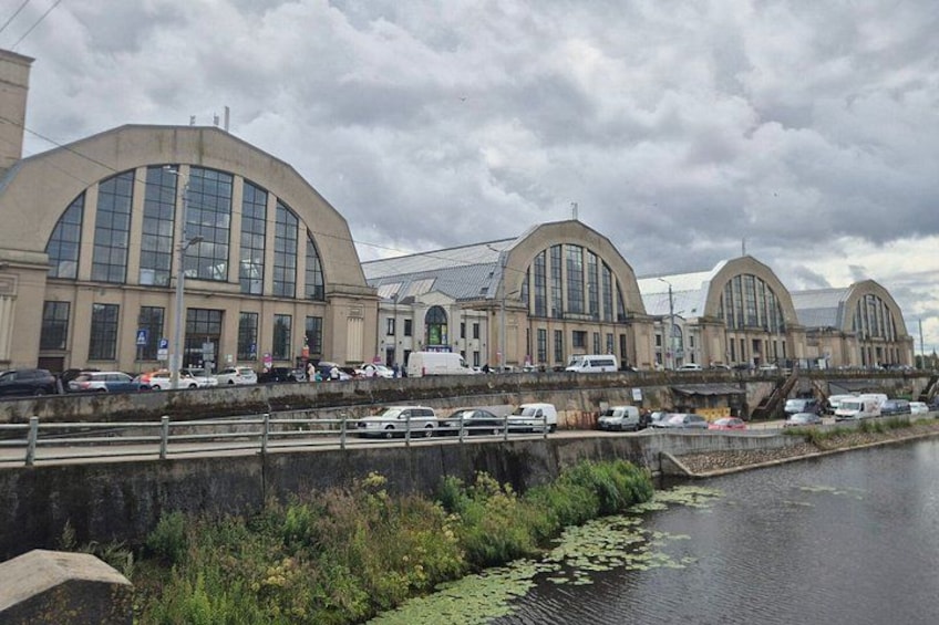 A large industrial building with arched windows and a canal with water lilies. 2