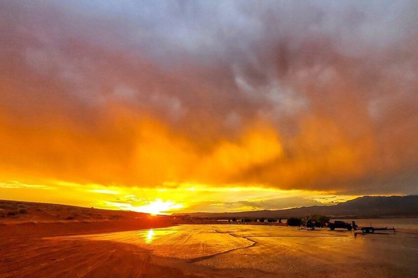 A sunset over a desert landscape with a road and distant structures. 4