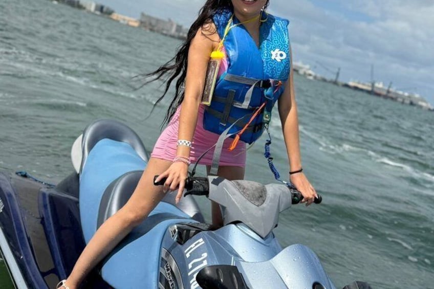 Una persona en un jet ski con chaleco salvavidas, usando shorts rosa y una camiseta azul. 5
