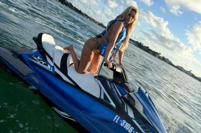 Una persona en un jet ski, con una masa de agua y una orilla distante al fondo. 1