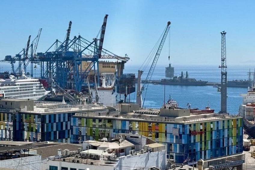 A port with cargo containers, cranes, and a cruise ship. 4