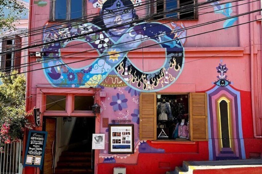 A colorful building with a mural of a face and a shop entrance. 5