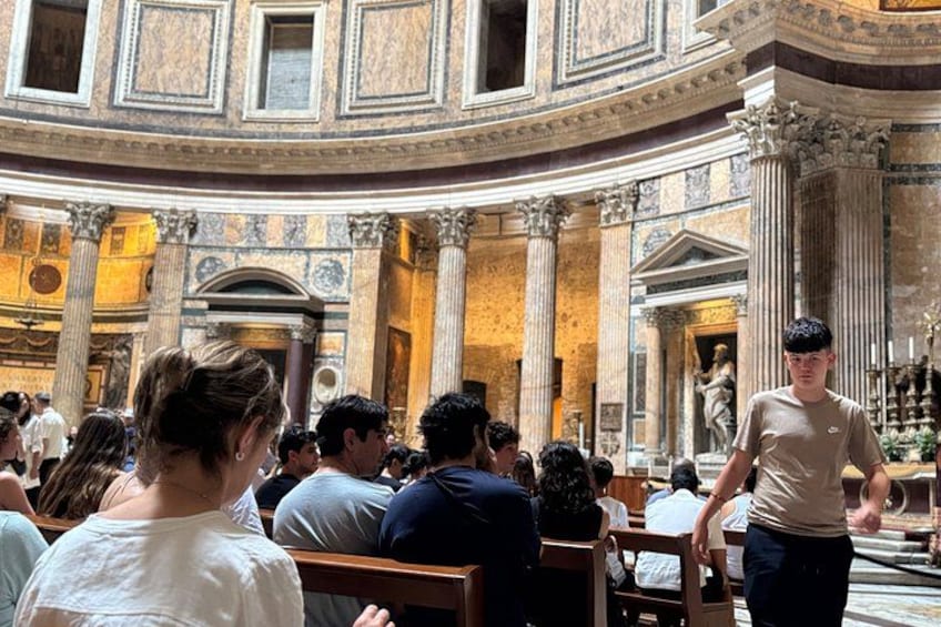 A crowded indoor space with classical architecture, including columns and arches. 2