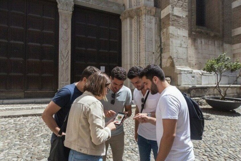 Un groupe de personnes se tient sur une rue pavée, devant un bâtiment doté de grandes portes en bois. 4