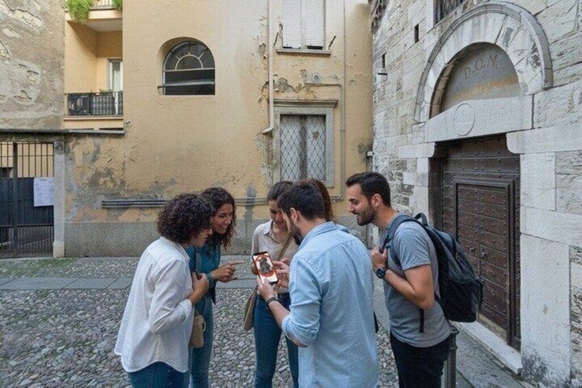 Un groupe de personnes se tient sur une rue pavée, dans un quartier urbain bordé de bâtiments historiques. 3