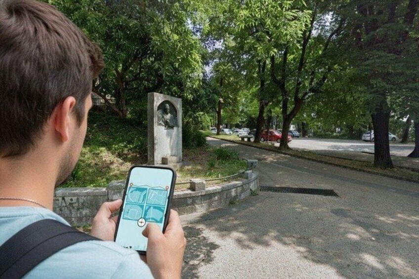 Une personne utilisant un téléphone intelligent dans un parc, près d’une statue et d’arbres. 1