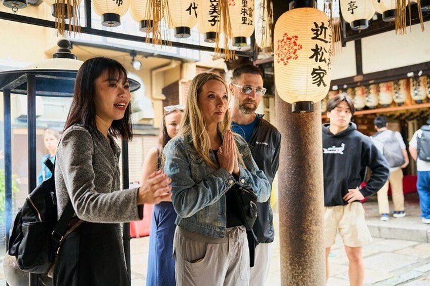 A group of people standing near a traditional Japanese lantern with Japanese characters. 3