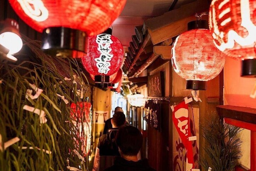 A narrow alleyway with red lanterns hanging overhead. 5