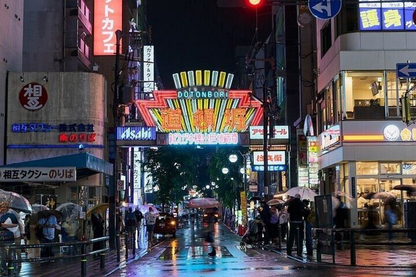 Une rue mouillée la nuit, illuminée par des enseignes au néon, avec un passage piéton. 2
