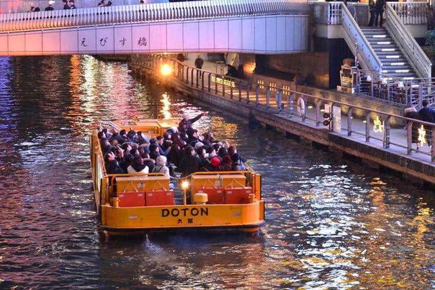 A yellow boat with 'DOTON' written on it, carrying passengers on a river. 4