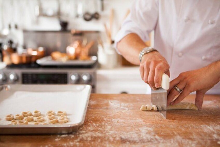 A person rolling dough on a floured surface with a rolling pin, and a baking tray with dough shapes in the background. 3