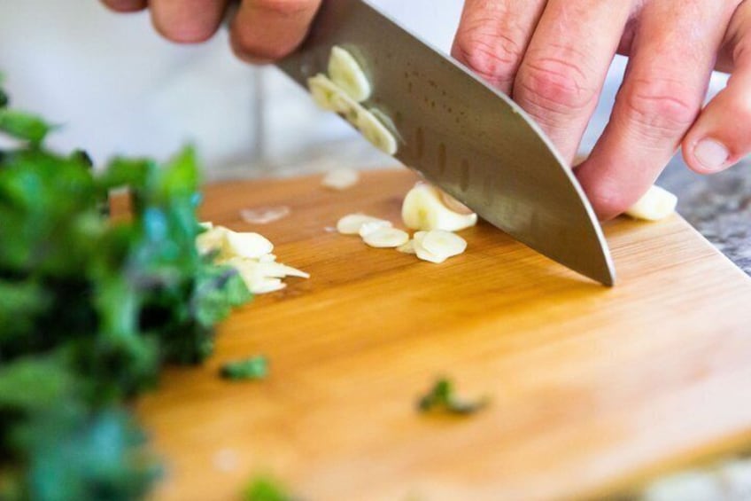 A person chopping garlic on a wooden cutting board. 5