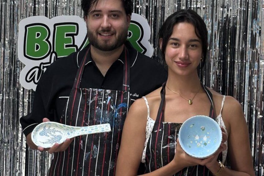 A person holding a white bowl with a spoon, standing in front of a metallic backdrop with the letters 'BEAR' visible. 3