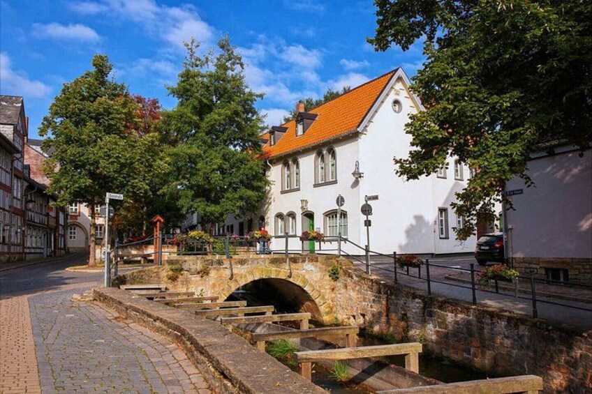 A stone bridge over a canal, surrounded by trees and historic buildings. 5