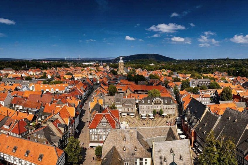 A town with red-roofed buildings, a prominent church, and a hill in the background. 2