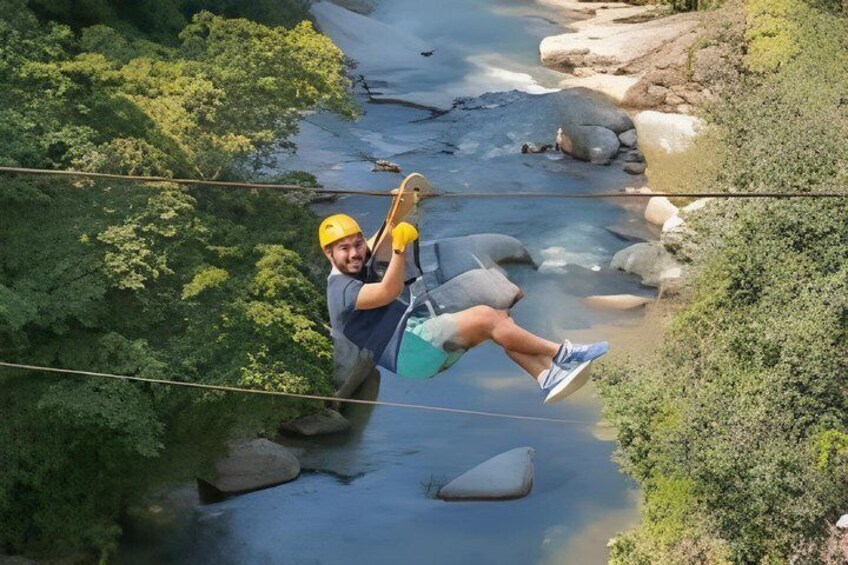 A person zip-lining over a river with greenery on either side. 1