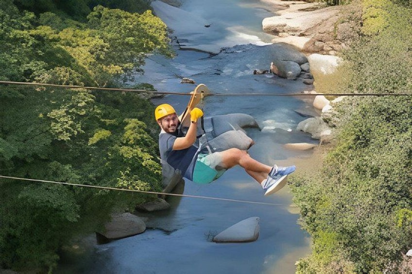 Una persona haciendo tirolesa sobre un río con rocas y vegetación. 1