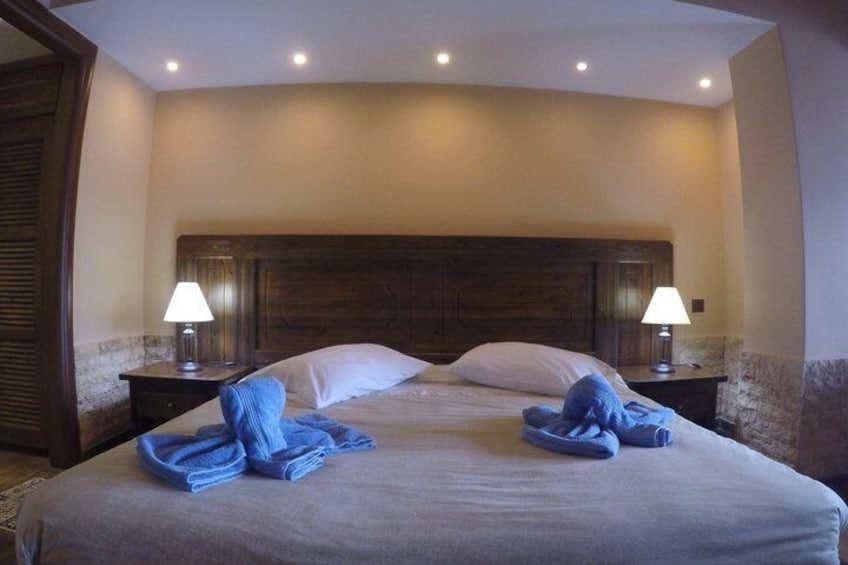 A hotel room with a large bed, two bedside lamps, and folded towels on the bed. 5