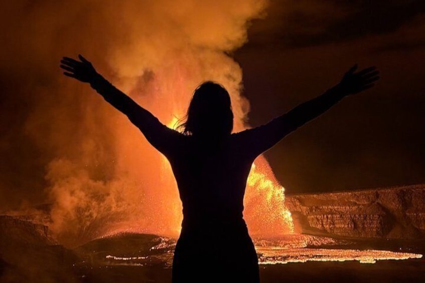 A silhouette of a person with arms outstretched in front of a volcanic eruption. 3