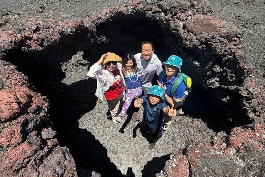 A group of people standing in a volcanic crater surrounded by rugged terrain. 4