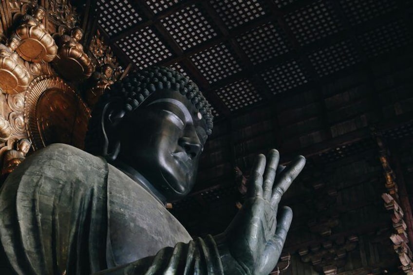 A large statue with a raised hand, set against a backdrop of ornate architecture and a patterned ceiling. 4