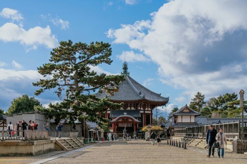 A traditional Japanese temple with a large tree in the foreground and a clear sky. 5