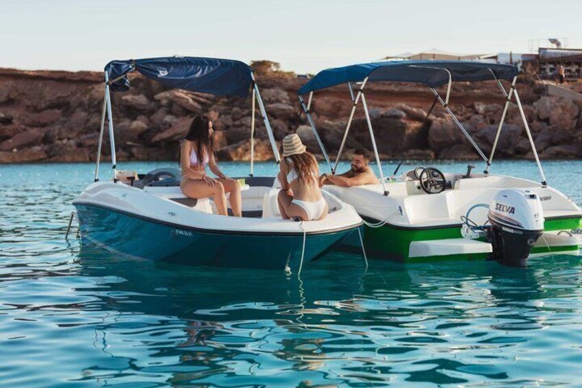Two motorboats on calm water with rocky cliffs in the background. 2