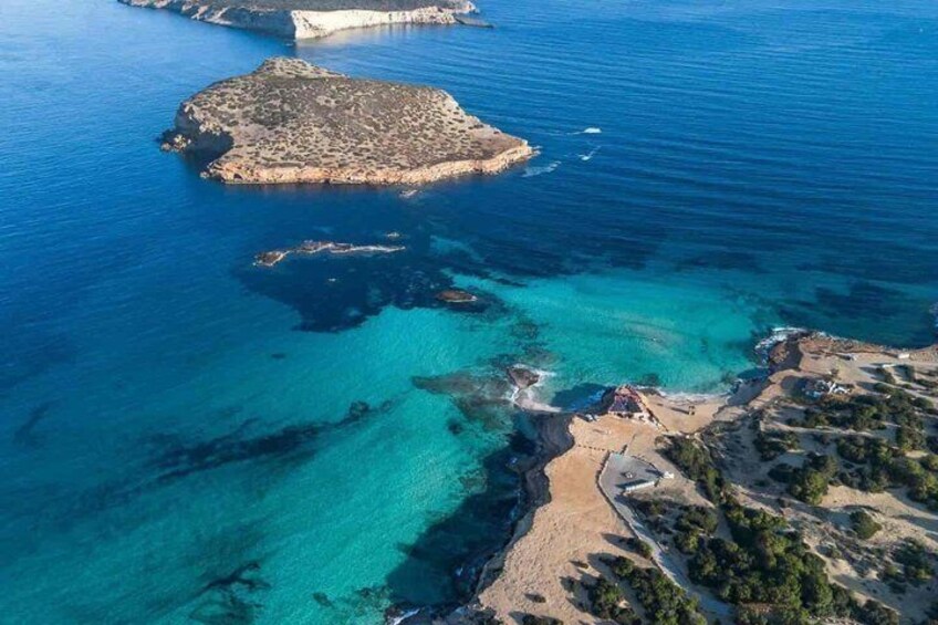 An aerial view of a coastal area with clear turquoise waters, a sandy beach, and a rocky island. 5