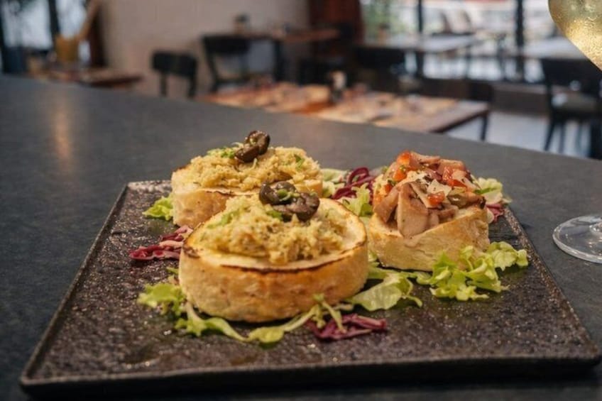 Une assiette contenant du pain farci et une salade, posée sur une table sombre dans un restaurant. 2