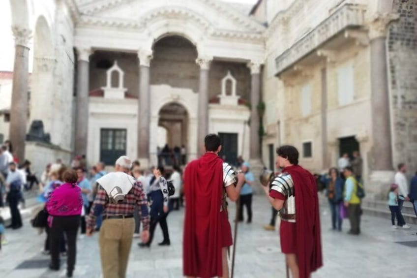 Un bâtiment historique doté d’arcades et de colonnes, une foule de personnes et des individus vêtus de manteaux rouges. 4