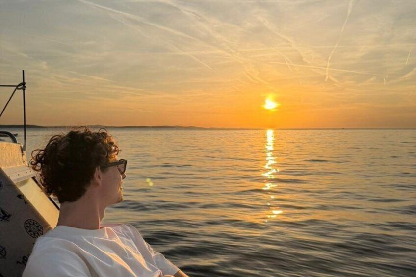 A person on a boat during sunset with the sun reflecting on the water. 5