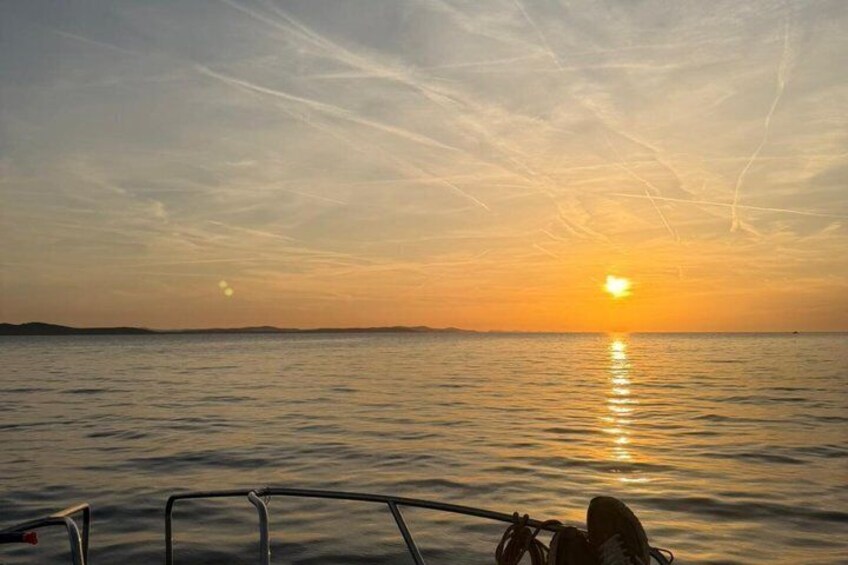 A sunset over calm water with a boat in the foreground. 1