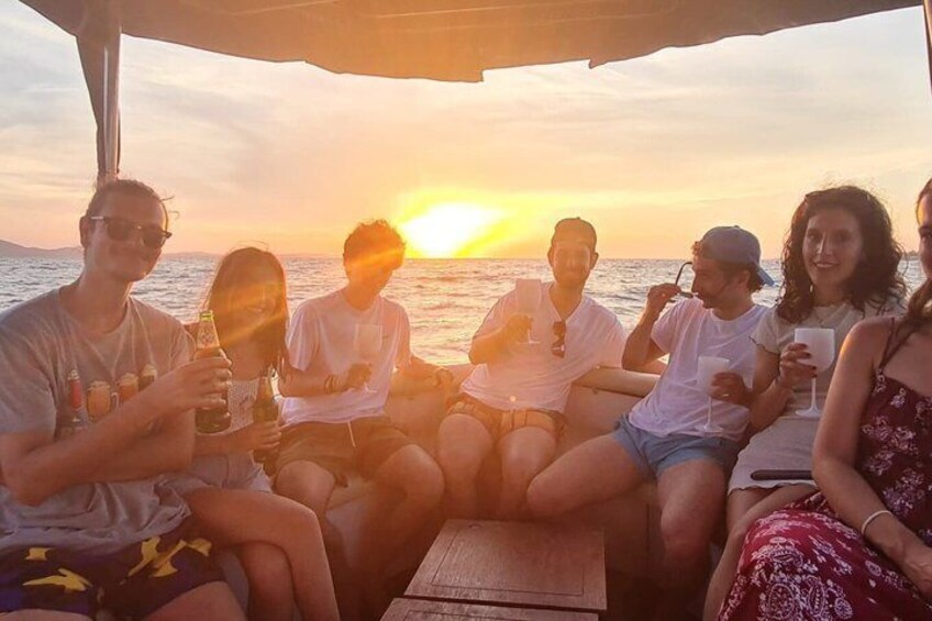 A group of people sitting on a boat during sunset. 3