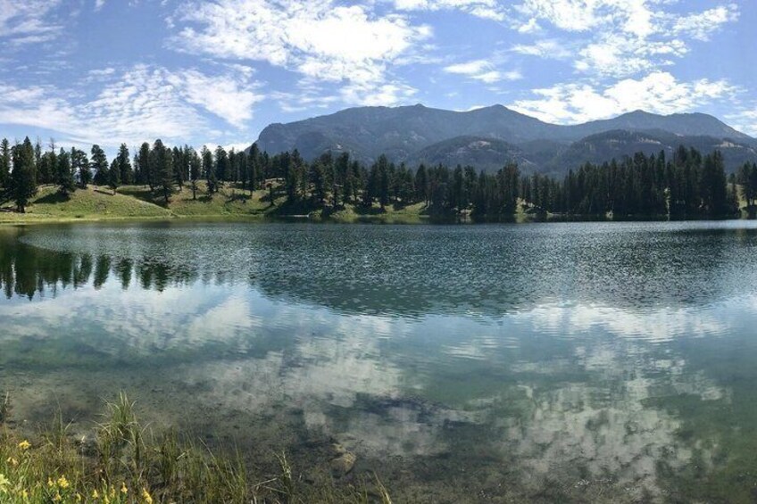 Ein klarer See mit Bergen im Hintergrund und einer bewaldeten Gegend. 2