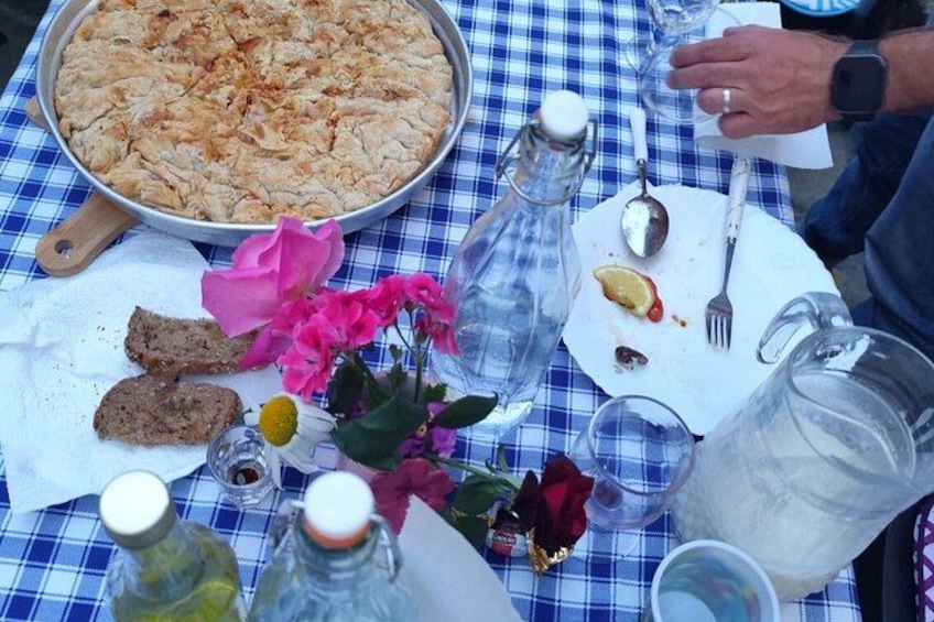 A meal with bread, a pan of food, a pitcher, a plate with a lemon, and a bottle. 3