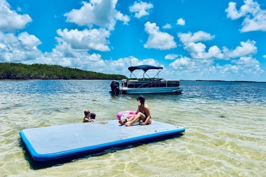 A clear blue sea with a boat and a floating platform with people on it. 1