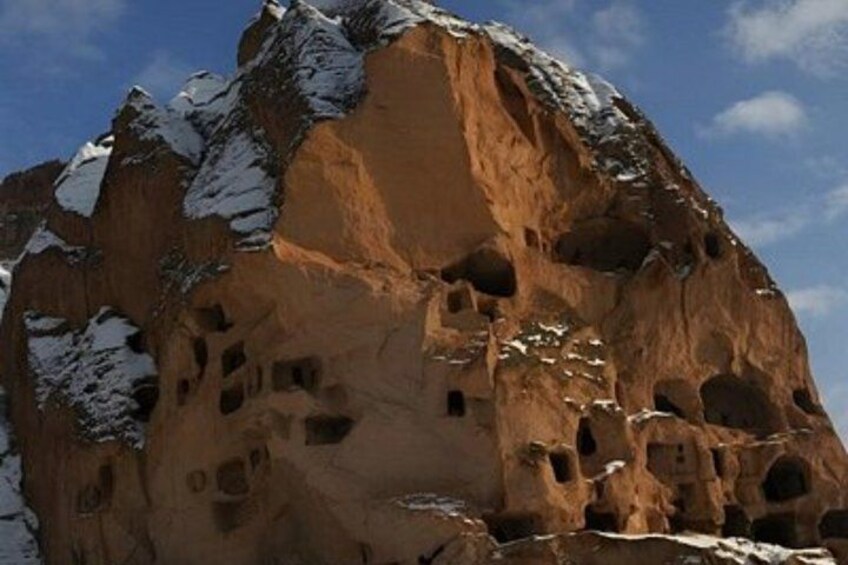A rock formation with multiple caves and snow patches. 5
