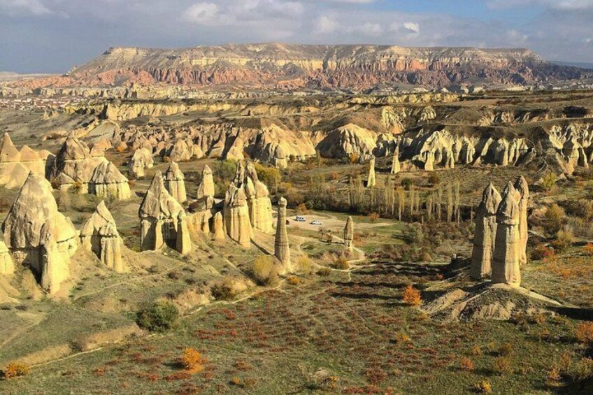 Un paisaje con numerosas formaciones rocosas, cielo despejado y colinas al fondo. 2